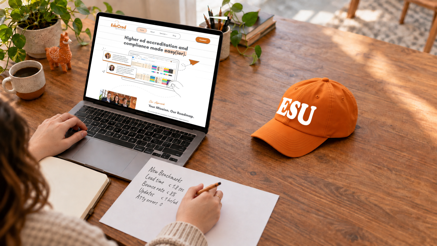A laptop on a desk is open to our new website. An orange hat with "ESU" sits next to it.